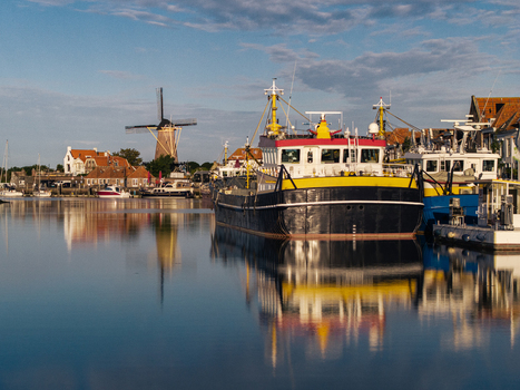 Aerial view of a cargo ship moored in the harbor of Zierikzee with a traditional windmill and historic buildings in the background in Zierikzee Zeeland Netherlands. Aerial view of a cargo ship moored in the harbor of Zierikzee with a traditional windmill and historic buildings in the background in Zierikzee Zeeland Netherlands.