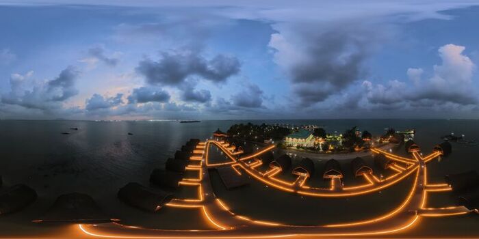 Aerial view of Pulau Lima Resort featuring illuminated overwater bungalows connected by glowing wooden walkways over the sea at twilight in Kasemen Banten Indonesia. Aerial view of Pulau Lima Resort featuring illuminated overwater bungalows connected by glowing wooden walkways over the sea at twilight in Kasemen Banten Indonesia.