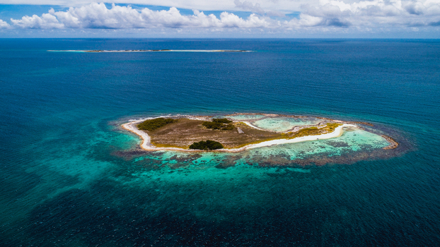 Aerial view of the Los Roques archipelago featuring a small island with white sand beaches turquoise waters and coral reefs in Los Roques Dependencias Federales Venezuela. Aerial view of the Los Roques archipelago featuring a small island with white sand beaches turquoise waters and coral reefs in Los Roques Dependencias Federales Venezuela.