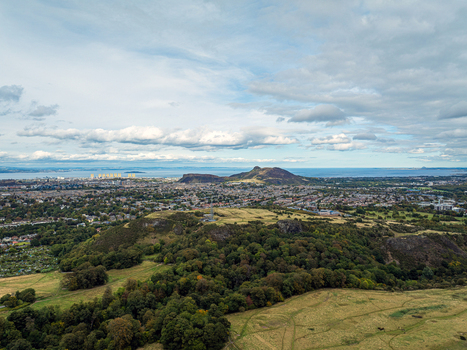 Aerial view of Braid Hills with lush green slopes and trees overlooking the city skyline of Edinburgh Scotland United Kingdom. Aerial view of Braid Hills with lush green slopes and trees overlooking the city skyline of Edinburgh Scotland United Kingdom.