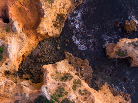 Aerial view of the dramatic golden limestone cliffs and rock formations of Ponta da Piedade surrounded by the deep blue Atlantic Ocean in Lagos Faro Portugal.