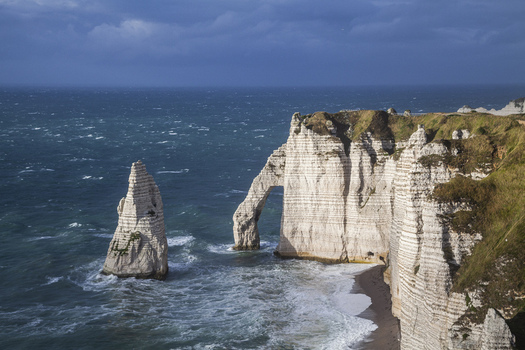 Aerial view of dramatic cliffs with the natural arch of &Eacute;tretat piercing the skyline waves crashing against the chalk formations &Eacute;tretat Normandy France.