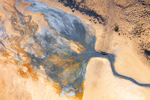 Aerial view of Hverir geothermal field showing vibrant mineral deposits steaming vents and colorful sulfurous soil patterns in the volcanic landscape of Reykjahlid Thingeyjarsveit Iceland.