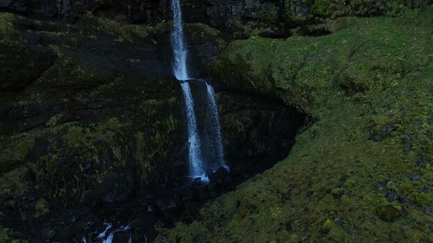 Aerial view of Bugsfoss waterfall cascading down mossy cliffs Iceland.