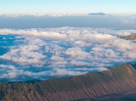 Aerial view of Mount Bromo with its volcanic crater rim rising above a vast sea of clouds in the early morning light in Tosari East Java Indonesia.
