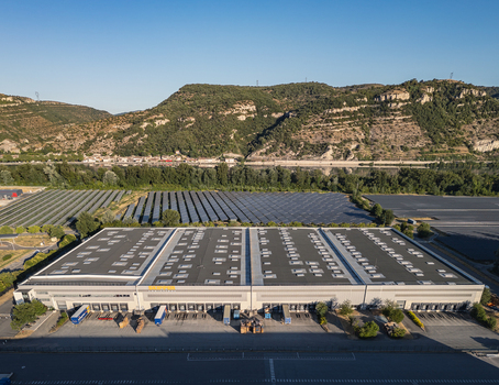 Le Pouzin France 04 July 2026 Aerial view of the SKIPPER Logistique warehouse and distribution center featuring large rooftops with skylights loading docks and solar panels near rolling hills. Le Pouzin France 04 July 2026 Aerial view of the SKIPPER Logistique warehouse and distribution center featuring large rooftops with skylights loading docks and solar panels near rolling hills.