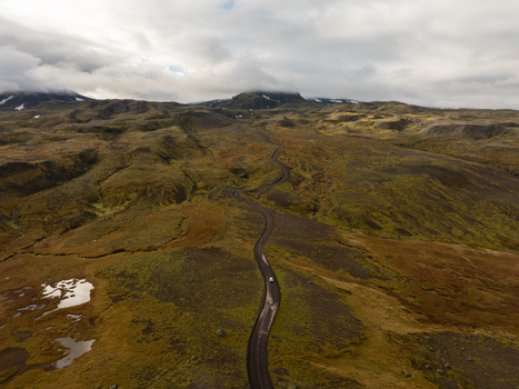 Aerial view of a solitary road winds through the rugged moss covered terrain under a vast sky Snæfellsnes Eyja og Miklaholtshreppur Iceland. Aerial view of a solitary road winds through the rugged moss covered terrain under a vast sky Snæfellsnes Eyja og Miklaholtshreppur Iceland.