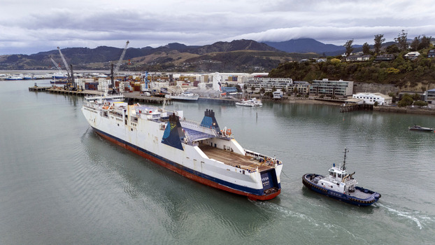 Nelson New Zealand 19 February 2026 Aerial view of Port Nelson with a large cargo ship being assisted by a tugboat near the industrial docks and coastal hills. Nelson New Zealand 19 February 2026 Aerial view of Port Nelson with a large cargo ship being assisted by a tugboat near the industrial docks and coastal hills.