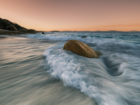 View of the surf washing over a large rock on the sandy beach at sunset in Frenchman Bay Western Australia Australia. View of the surf washing over a large rock on the sandy beach at sunset in Frenchman Bay Western Australia Australia.