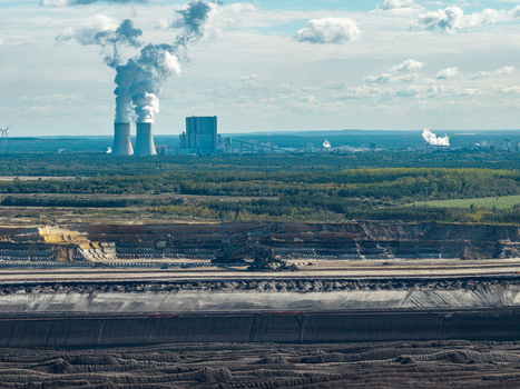 Aerial view of Tagebau Welzow Sud brown coal open pit mine with deep excavation layers heavy machinery and a power plant emitting smoke in the distance Spremberg Brandenburg Germany. Aerial view of Tagebau Welzow Sud brown coal open pit mine with deep excavation layers heavy machinery and a power plant emitting smoke in the distance Spremberg Brandenburg Germany.