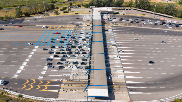 Aerial view of the Autostrada A1 Melegnano toll plaza featuring multiple vehicle access lanes and highway infrastructure in Melegnano Lombardy Italy.