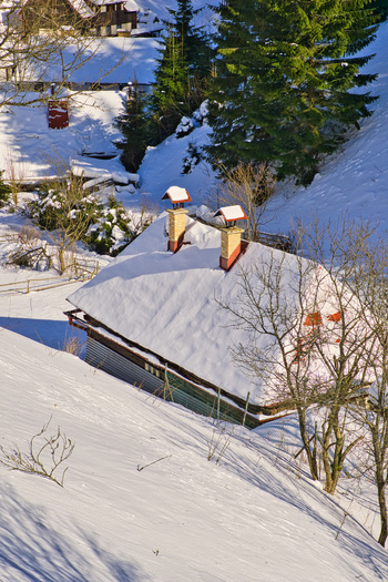 View of a cozy snow dusted cabin nestled in a winter landscape its chimney tops peeking through the thick blanket of white Moce Banska Bystrica Region Slovakia.