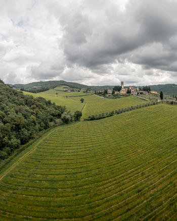 Aerial view of the historic village of Passignano nestled among rolling green vineyards and olive groves under a cloudy sky in Passignano Toscana Italy. Aerial view of the historic village of Passignano nestled among rolling green vineyards and olive groves under a cloudy sky in Passignano Toscana Italy.