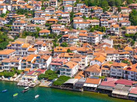 Aerial view of the historic old town of Ohrid with traditional white houses terracotta roofs waterfront restaurants and small boats on Lake Ohrid Ohrid North Macedonia.