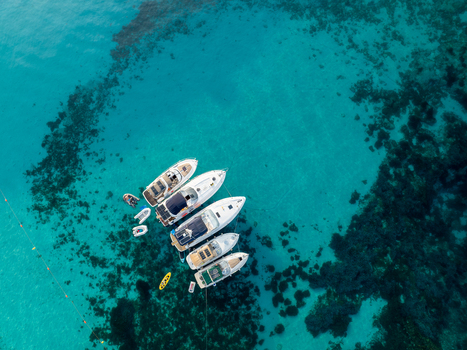 Aerial view of boats floating on the crystal clear turquoise water of the Blue Lagoon a stunning contrast to the dark rocky seabed Blue lagoon Comino Malta. Aerial view of boats floating on the crystal clear turquoise water of the Blue Lagoon a stunning contrast to the dark rocky seabed Blue lagoon Comino Malta.