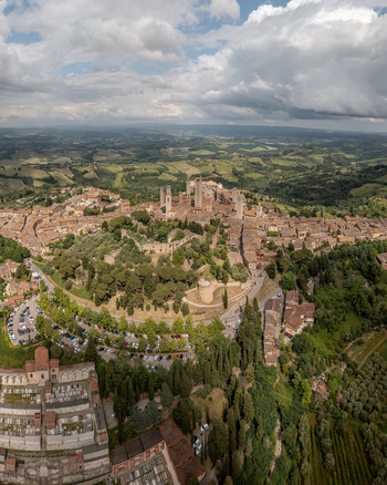 Aerial view of the historic medieval town with its iconic stone towers surrounded by lush rolling hills olive groves and vineyards in San Gimignano Tuscany Italy. Aerial view of the historic medieval town with its iconic stone towers surrounded by lush rolling hills olive groves and vineyards in San Gimignano Tuscany Italy.