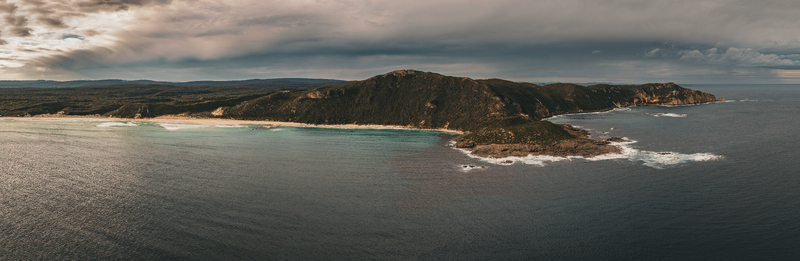 Aerial view of Conspicuous Cliff featuring rugged coastal cliffs turquoise ocean waters crashing waves and dense vegetation under a dramatic sky in Nornalup Western Australia Australia. Aerial view of Conspicuous Cliff featuring rugged coastal cliffs turquoise ocean waters crashing waves and dense vegetation under a dramatic sky in Nornalup Western Australia Australia.