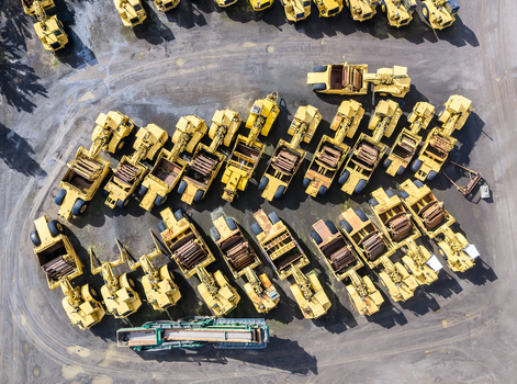 Aerial view of a large fleet of yellow construction scrapers and earthmoving machinery parked in an organized lot in Woodburn Oregon United States. Aerial view of a large fleet of yellow construction scrapers and earthmoving machinery parked in an organized lot in Woodburn Oregon United States.