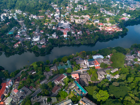 Aerial view of Kandy Lake surrounded by lush greenery urban buildings and winding roads in Kandy Central Province Sri Lanka. Aerial view of Kandy Lake surrounded by lush greenery urban buildings and winding roads in Kandy Central Province Sri Lanka.
