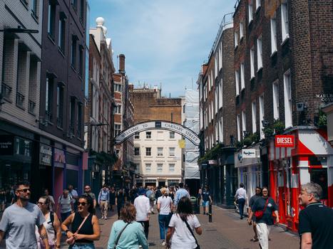 London United Kingdom 20 June 2025 View of a bustling street scene where pedestrians stroll beneath an archway flanked by brick buildings and vibrant storefronts under a bright sky. London United Kingdom 20 June 2025 View of a bustling street scene where pedestrians stroll beneath an archway flanked by brick buildings and vibrant storefronts under a bright sky.