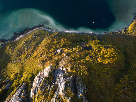Aerial view of the rocky mountain peak and autumn foliage overlooking a turquoise bay and sandy beach in Leknes Nordland Norway. Aerial view of the rocky mountain peak and autumn foliage overlooking a turquoise bay and sandy beach in Leknes Nordland Norway.