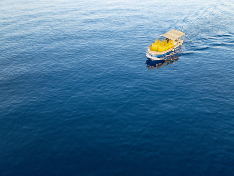 Aerial view of a boat carrying bright yellow objects glides through the deep blue sea creating a striking contrast of color Ghajnsielem Gozo Malta. Aerial view of a boat carrying bright yellow objects glides through the deep blue sea creating a striking contrast of color Ghajnsielem Gozo Malta.