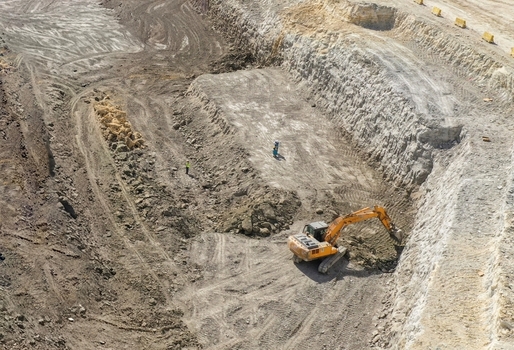 Aerial view of an orange excavator digging at a construction site with workers in Avcilar Istanbul Turkiye. Aerial view of an orange excavator digging at a construction site with workers in Avcilar Istanbul Turkiye.