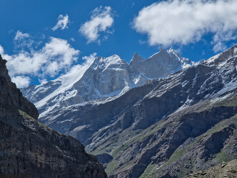 View of the rugged snow capped peaks and rocky slopes near the Penzi La road in the Zanskar valley under a bright blue sky with scattered clouds Zanskar Ladakh India.