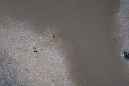 Aerial view of a sandy shoreline meeting a calm body of water in Latvia.