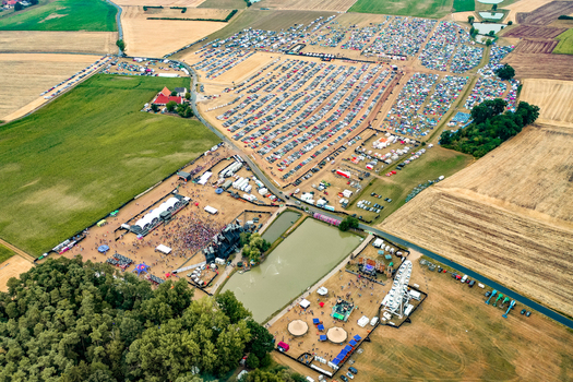 Herzogenaurach Germany 22 July 2022 Aerial view of Open Beatz Festival featuring multiple stages large crowds of people and vast camping and parking areas set amidst rural fields. Herzogenaurach Germany 22 July 2022 Aerial view of Open Beatz Festival featuring multiple stages large crowds of people and vast camping and parking areas set amidst rural fields.