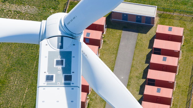 Aerial view of a wind turbine nacelle and blades above red shipping containers on a green field in Middelharnis South Holland Netherlands. Aerial view of a wind turbine nacelle and blades above red shipping containers on a green field in Middelharnis South Holland Netherlands.