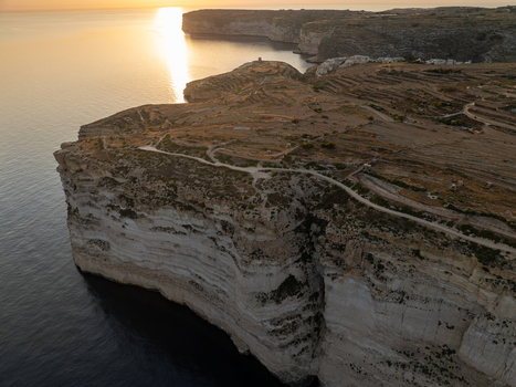 Aerial view of the rugged sun kissed cliffs contrasting with the deep blue sea highlighting the natural beauty of Sanap Cliffs Munxar Gozo Malta. Aerial view of the rugged sun kissed cliffs contrasting with the deep blue sea highlighting the natural beauty of Sanap Cliffs Munxar Gozo Malta.