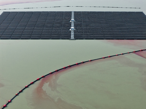 Aerial view of a large floating solar farm installed on a calm lake with a containment boom line visible in the water in Dulmen North Rhine Westphalia Germany. Aerial view of a large floating solar farm installed on a calm lake with a containment boom line visible in the water in Dulmen North Rhine Westphalia Germany.