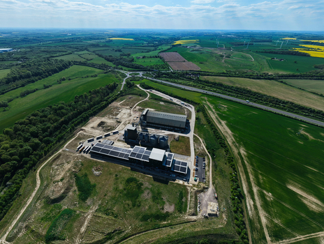 Aerial view of the Oat Milling Factory featuring industrial silos and solar panels surrounded by green fields and a highway in Kettering England United Kingdom. Aerial view of the Oat Milling Factory featuring industrial silos and solar panels surrounded by green fields and a highway in Kettering England United Kingdom.