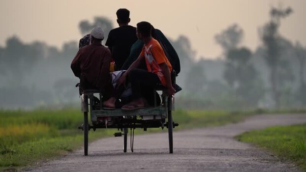 View of people riding a rickshaw on a rural road Bangladesh.