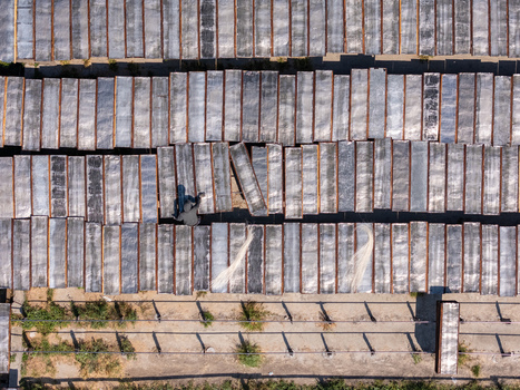 Aerial view of a worker tending to rows of drying noodles on racks in an agricultural field in Polanharjo Central Java Indonesia.