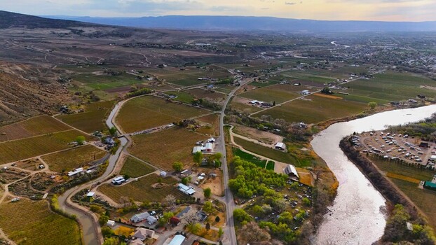 Aerial view of a meandering river reflecting the sky cutting through vineyards and orchards nestled against the backdrop of distant mountains Palisade Colorado USA. Aerial view of a meandering river reflecting the sky cutting through vineyards and orchards nestled against the backdrop of distant mountains Palisade Colorado USA.