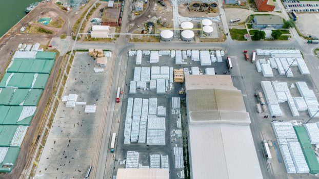 Aerial view of an industrial port area with large stacks of white cargo bags warehouses and transport trucks in Sabac Vojvodina Serbia. Aerial view of an industrial port area with large stacks of white cargo bags warehouses and transport trucks in Sabac Vojvodina Serbia.
