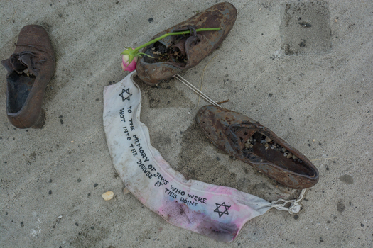 View of the Shoes on the Danube Bank memorial featuring iron shoes and a commemorative ribbon with a Star of David on the concrete embankment in Budapest Hungary.