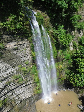 Aerial view of the waterfall in Sitakund with people swimming in the pool at the base of the rocky cliff surrounded by lush green vegetation in Sitakund Chittagong Division Bangladesh. Aerial view of the waterfall in Sitakund with people swimming in the pool at the base of the rocky cliff surrounded by lush green vegetation in Sitakund Chittagong Division Bangladesh.