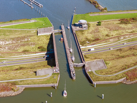 Aerial view of Naviduct Krabbersgat with sailboats navigating the lock system surrounded by green embankments and roads in Lelystad Flevoland Netherlands. Aerial view of Naviduct Krabbersgat with sailboats navigating the lock system surrounded by green embankments and roads in Lelystad Flevoland Netherlands.
