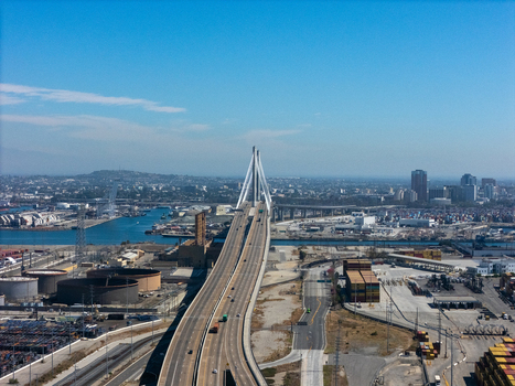 Aerial view of the Gerald Desmond Bridge spanning the industrial Port of Long Beach with shipping containers and highway traffic in Long Beach California United States. Aerial view of the Gerald Desmond Bridge spanning the industrial Port of Long Beach with shipping containers and highway traffic in Long Beach California United States.