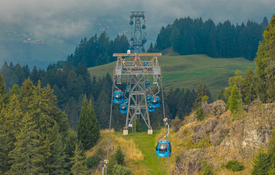 Compatsch Italy 18 September 2026 Aerial view of Alpe di Siusi cable car gondolas crossing green alpine meadows in the Dolomites.