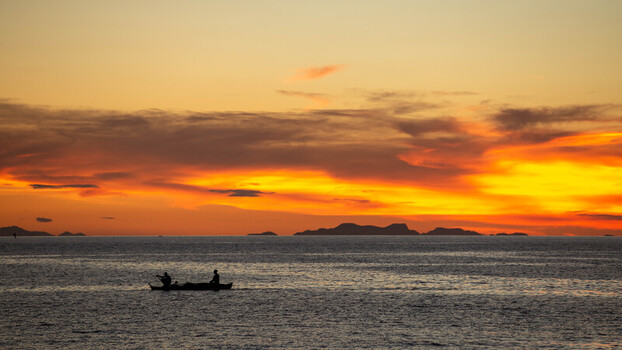 View of fishermen in a small boat on the sea at sunset near Bantayan Island Cebu Central Visayas Philippines. View of fishermen in a small boat on the sea at sunset near Bantayan Island Cebu Central Visayas Philippines.