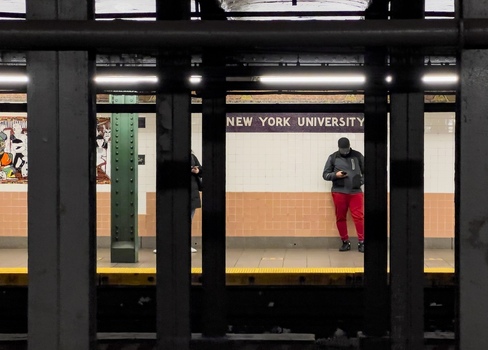 New York United States 14 May 2026 View of the New York University subway station platform with people waiting and looking at their phones behind structural pillars. New York United States 14 May 2026 View of the New York University subway station platform with people waiting and looking at their phones behind structural pillars.