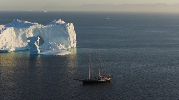 Aerial view of sailboat near arch iceberg Greenland. Aerial view of sailboat near arch iceberg Greenland.