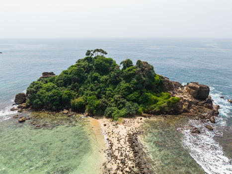 Aerial view of Devil s Rock a lush green rocky island surrounded by turquoise ocean waters and a small sandy beach in Ahangama Southern Province Sri Lanka. Aerial view of Devil s Rock a lush green rocky island surrounded by turquoise ocean waters and a small sandy beach in Ahangama Southern Province Sri Lanka.