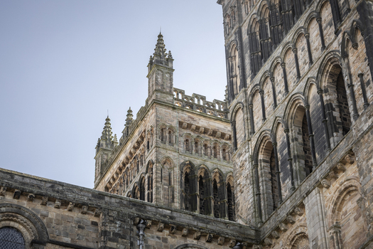 View of Durham Cathedral showing its historic stone towers intricate Romanesque arches and weathered masonry against a clear sky in Durham England United Kingdom. View of Durham Cathedral showing its historic stone towers intricate Romanesque arches and weathered masonry against a clear sky in Durham England United Kingdom.
