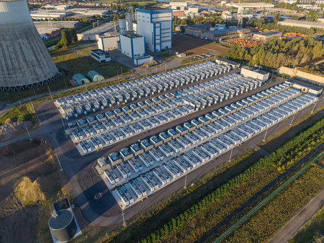 Aerial view of the Cargovil battery energy storage system with rows of white containers a cooling tower and industrial buildings in an urban landscape in Vilvoorde Vlaanderen Belgium. Aerial view of the Cargovil battery energy storage system with rows of white containers a cooling tower and industrial buildings in an urban landscape in Vilvoorde Vlaanderen Belgium.