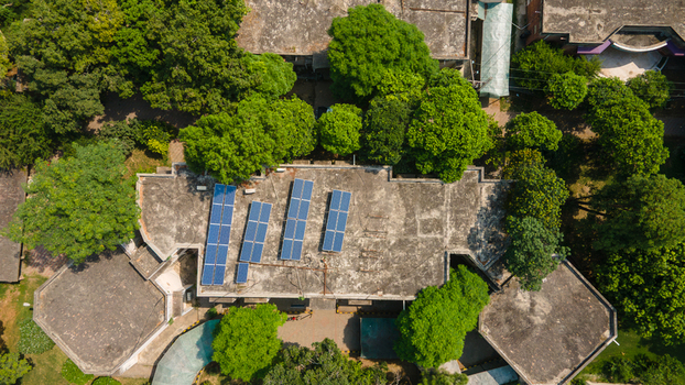Lahore Punjab Pakistan 08 September 2026 Aerial view of a government office building featuring solar panels installed on its flat roof surrounded by lush green trees in an urban setting.